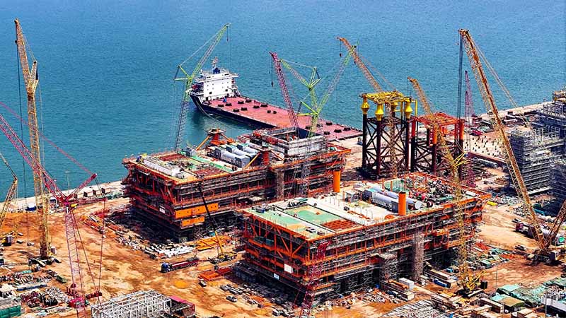 An aerial view of massive offshore steel structures and modules at a shipbuilding yard, demonstrating high-end surface preparation and coating standards for marine engineering.