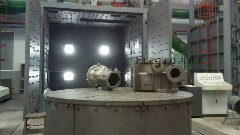 Massive industrial machinery casting positioned on an automated heavy-duty trolley system before entering the blast chamber for pre-machining descaling.